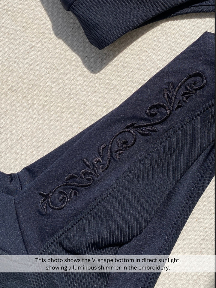 Bikini bottom V-shape in black, close up of embroidery and rib fabric in sunlight